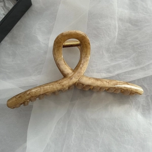 Dettaglio di un grande fermaglio per capelli con venature del legno e molla dorata
