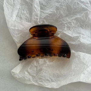 Detailed view of the smooth tortoiseshell amber fan-shaped hair claw on white paper