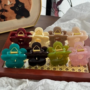 Detailed set of eight colorful floral hair clips arranged on a textured wooden tray
