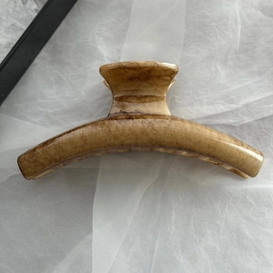 Dettaglio di una grande molletta per capelli marrone marmorizzata su rete bianca morbida