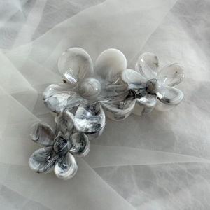 Detail der Tintenmarmor-Textur und des Blumendesigns an einer großen Haarklammer