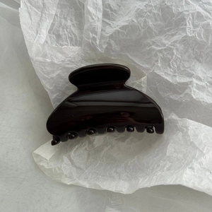 Close-up of polished dark coffee hair claw clip showing glossy resin surface and inner teeth