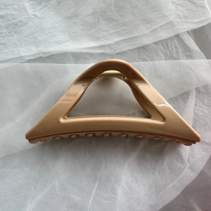 Close-up of soft silicone shark hair claw clip in tan color with triangle hollow design