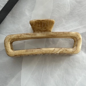 Dettaglio della grande pinza rettangolare con elegante texture in marmo beige