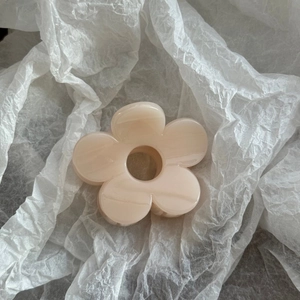 Detail of a creamy beige floral hair claw clip with marble texture on soft paper