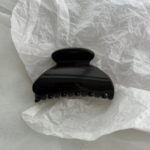 Close-up of a glossy black hair claw clip featuring a sleek curved design and dense teeth
