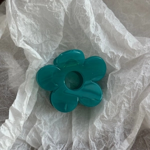 Detail shot of marble textured blue flower hair claw clip on white wrinkled paper background