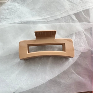 Detail of soft silicone rectangle hair claw clip in khaki on white tulle background