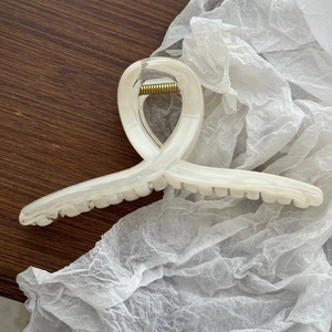 Dettaglio di un grande fermaglio per capelli marmorizzato con molla in metallo dorato elastica