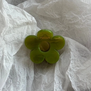 Top view of a grass green translucent flower-shaped hair claw clip with a metal spring