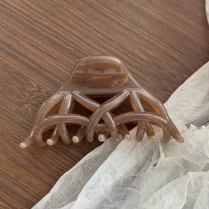Grosse pince à cheveux ambre foncé avec des lignes géométriques sur une surface en bois