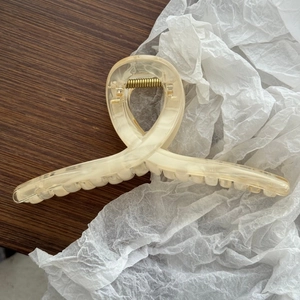 Dettaglio di un grande fermaglio per capelli marmorizzato con molla in metallo dorato