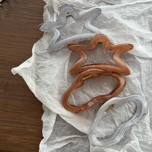 Macro detail of large marble star and wave hair claws in gray and amber resin
