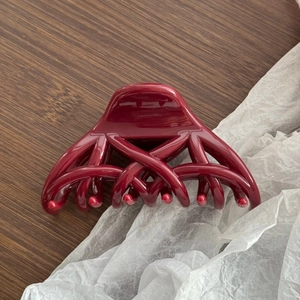 Détail d'une élégante pince à cheveux bordeaux brillant sur un fond en bois