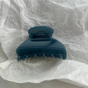 Detail showing the glossy dark blue fan-shaped hair claw clip on a white background