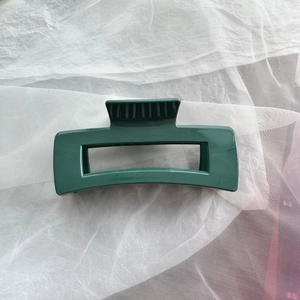 Detail view of a dark green square soft silicone hair claw clip on white tulle fabric