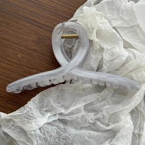 Dettaglio di un grande fermaglio per capelli da 15 cm con texture marmorea e molla oro