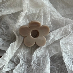 Close-up of minimalist milk-tea colored flower hair claw clip on white textured paper