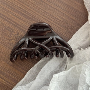 Détail d'une pince à cheveux marron foncé au design croisé brillant sur bois