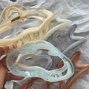 Close-up of matte star and cloud hair claws with golden metal springs on white fabric