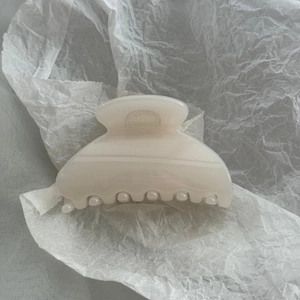 Close-up of cream glossy fan-shaped hair claw clip with smooth polished surface and firm grip