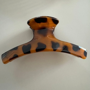 Macro detail of the glossy amber leopard pattern resin hair claw clip with smooth texture
