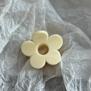 Detailed close-up of a creamy white floral hair claw clip on white textured paper