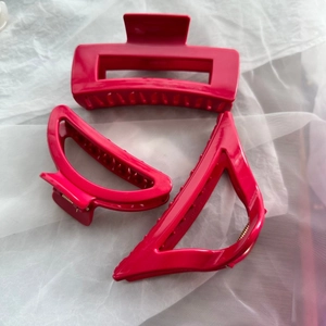 Detailed view of three bright pink geometric hair claws in rectangular and half-moon shapes