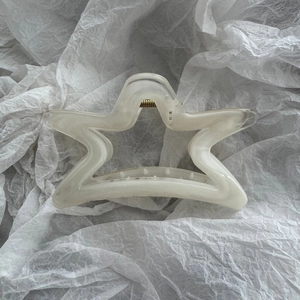 Macro shot of cream white star hair claw with marbled acetate texture and metal spring detail