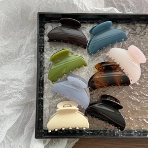 Glossy fan-shaped hair claws in eight elegant colors on a stylish glass tray