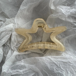 Macro detail of large star-shaped hair claw clip with amber resin texture and gold spring