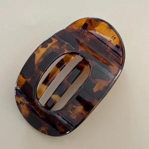 Detail shot of a glossy tortoiseshell hair claw clip with a hollow oval design and pattern