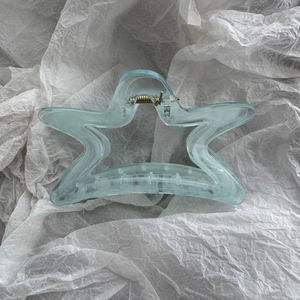 Detail of light blue translucent star hair claw clip with golden metal spring