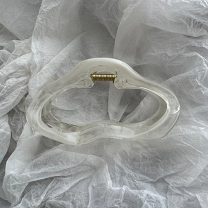 Close-up of large cloud-shaped hair claw clip with white marble texture and gold spring