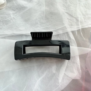 Detail view of a black soft silicone hair claw clip on white fabric background