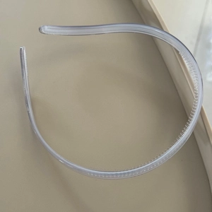Close-up of minimalist transparent plastic headband showing non-slip inner teeth detail