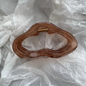 Macro detail of amber brown wavy star hair claw clip with golden metal spring