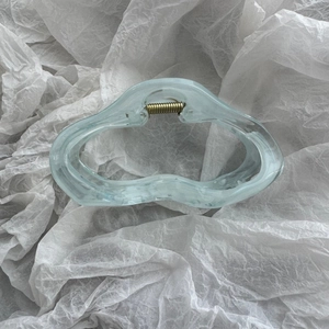 Close-up of light blue translucent hair claw clip with wavy lines and golden spring