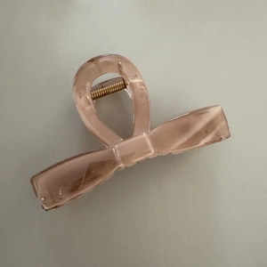 Détail macro d'une pince à cheveux nœud rose pêche avec ressort métallique doré robuste