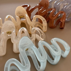 Detailed view of large wavy resin hair claw clips in soft Morandi colors with gold spring