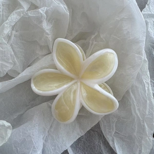 Makroaufnahme einer marmorierten Haarklammer in Frangipani-Form mit matten Blütenblättern