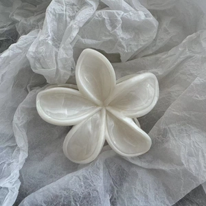 Makroaufnahme einer weißen Blumenhaarklammer mit Perlglanz-Marmorierung auf Papier