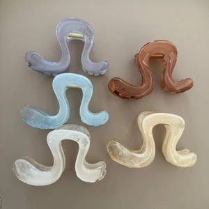 Flat lay of colorful S-shaped hair claws in pastel tones with gold metal springs