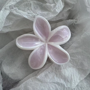 Nahaufnahme einer Haarklammer in Blumenform aus Harz mit rosa Marmorierungseffekt