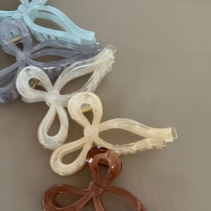 Close-up of marble pattern bow hair claws in five colors on a neutral matte background
