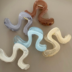 Flat lay of five wavy acrylic hair claws in assorted pastel colors with gold springs
