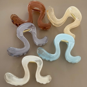 Close-up of wavy S-shaped hair claws in five translucent Morandi colors with gold springs