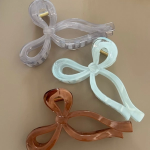 Three large marble-textured bow hair claws in grey, mint green, and brown colors