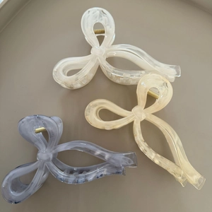 Detailed view of three marble-patterned bow hair claws in ivory, champagne, and smoky grey