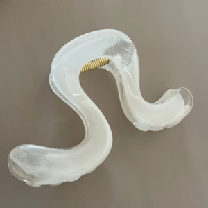 Macro shot of S-shaped hair claw clip in white marble pattern with golden spring